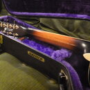 Kytara v černém kufru s fialovou vnitřní výplní. Na hlavě nástroje je viditelné logo Gretsch a nápis "NASHVILLE SERIES". Na vnější straně kufru je zl…