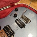 Stříbrná elektrická kytara v červeném etuýru. Nástroj má dva černé humbuckery, dvě černé otočné potenciometry a jeden přepínač. Je vybavena chromovan…