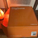 Oranžová papírová krabice s bílým nápisem Digitone a podtitulem Master of the digital method. Na povrchu je bílá schéma nástroje a logo Elektron. V d…