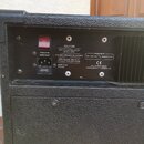 Zadní panel černého zesilovače s texturovaným povrchem. Je zde červený vypínač, vstup pro napájení a držák pojistky s nápisem MAINS FUSE 12A 250V. Na…
