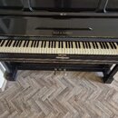 Černý piano v lakovaném provedení s klaviaturou. Na čelní straně nad klávesami je zlatý nápis KOCH & KORSELT. Dolní hrana nástroje vykazuje viditelné…