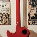 Zadní strana červené elektrické kytary s tvarem typu Les Paul. Na zadní straně hlavy je vyrazeno sériové číslo S13100148. Kytara má na zadní straně k…