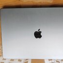 Stříbrný notebook v zavřeném stavu s kovovým povrchem. Uprostřed víčka je umístěno černé logo společnosti Apple. Povrch je hladký a bez viditelných p…
