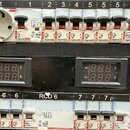 Fotografie zobrazuje elektrickou rozvaděčovou skříň s řadou jističů a dvěma digitálními voltmetrem/ampérmetry. Na jističích je vidět značka legrand a…