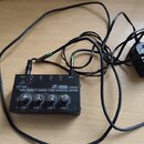 Černý kompaktní sluchátkový zesilovač s nápisem behringer MAZA AMP HA400 ULTRA-COMPACT 4-CHANNEL STEREO HEADPHONE AMPLIFIER. Zařízení má čtyři ovláda…