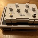 Bílý kytarový efekt s nápisem KERNOM RIDGE, umístěný na vlastním kartonovém obalu s nápisem KERNOM RIDGE OVERDRIVE. Zařízení má šest bílých otočných…