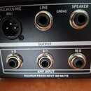Detail zadní strany černého elektronického zařízení s konektory. V horní sekci OUTPUT jsou tři výstupy s nápisy EMULATED MIC (BAL), LINE (UNBAL) a SP…