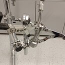 Detailní pohled na chromovaný mechanismus bicího pedálu. Na kovovém článku je vidět nápis "TAMA". Součástí mechanismu je černá gumová stupnička a nas…