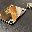 Kovový kryt v chromovaném provedení s rounded hranami a čtyřmi otvory pro šrouby. Uprostřed je vyryto logo Squier®. Vedle krytu jsou vidět tři kovové…