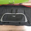 Černý textilní obal na hudební nástroj s červeným vnitřním okrajem. Uprostřed je umístěna kapsa s bílým lemováním a nápisem soundwear. Obal má dvě če…