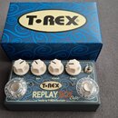 Kytarový efekt v šedém kovovém šasi s bílými ovládacími knoflíky. Na přední straně je nápis T-REX REPLAY BOX Delay a text Made by T-REX Denmark. V ho…