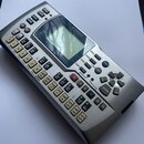 Stříbrný elektronický přístroj značky YAMAHA s LCD displejem a množstvím tlačítek. Na přední straně jsou viditelné nápisy jako SONG, PATTERN, MENU a…