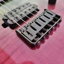 Detail elektrické kytary s růžovo-černým přechodem barvy na těle. Je vidět černý kobylník s pružinami a dva černé humbuckery. Na komponentech nejsou…