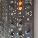 Černý syntetizátor značky ARTURIA s množstvím ovládacích knoflíků a posuvníků. Na panelu jsou viditelné nápisy jako OCTAVE, Wave, Timbre, Shape, Para…