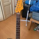 Elektrická kytara s jasně modrým tělem a hředníkem z tmavého dřeva. Na hlavě nástroje v přirozené barvě dřeva je viditelné logo Squier. Kytara má šes…