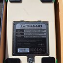 Spodní strana krémového efektpedálu s čtyřmi černými gumovými nožičkami. Na šedé kovové spodní desce je nápis T CHELICON DESIGNED AND ENGINEERED IN C…