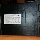 Zadní strana černého přístroje s texturovaným povrchem. Uprostřed je nalepený štítek s nápisem SPECIAL INSTRUCTIONS FOR BATTERY AMPLIFIER a následným…