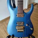 Modrá elektrická kytara s matným povrchem a hnědým hmatníkem. Nástroj má dva humbuckery, zlatý vibrační systém s páčkou a dvě ovládací knoflíky. Na z…