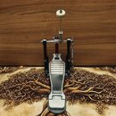 Krytý pohled na basový pedál s kovovou stlačovací plošší a dřevěným beaterem. Na spodní části plošně je viditelný nápis YAMAHA. Nástroj vykazuje mírn…