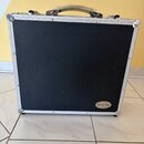 Černý transportní kufr s hliníkovými hranami a kovovými rohy. V pravém dolním rohu je oválný štítek s nápisem ROCKCASE. Povrch kufrů vykazuje drobné…