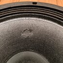 Detailní pohled na černý reproduktor s texturovanou membránou. V horní části je vidět černý plastový rám s otvory pro šrouby. V horní části membrány…