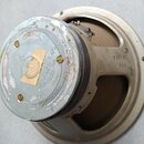 Fotografie zachycuje reproduktor s béžovým kovovým rámem a magnetem. Na rámu je vyražen nápis T-1217 DC8. Povrch magnetu je značně opotřebovaný, s od…