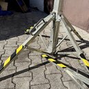 Kovový stativ s rozkládací základnou v přirozené barvě kovu. Nosné nohy jsou opatřeny žlutými a černými varovnými pruhy. Konstrukce vykazuje známky b…