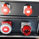 V hliníkovém přepravním kufru jsou umístěny dvě černé panely s elektrickými zásuvkami. Horní panel obsahuje dvě červené zásuvky značky MENNEKES s kry…