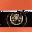 Fotografie zachycuje reproduktor v oranžovém kytarovém boxu. Na černé membráně je zlatý nápis CELESTION LOUDSPEAKERS, G12 16 ohms a Vintage 30. Po ob…
