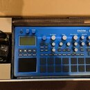 Modrý sampler KORG electribe MUSIC PRODUCTION STATION v originální kartonové krabici. Zařízení má LCD displej, několik ovládacích knoflíků a mřížku š…