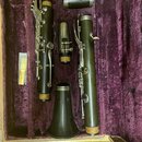 V purpurovém kufru jsou rozloženy části fagotu z tmavého dřeva s kovovými mechanismy. Na horním kusu je vidět nápis "A. Selmer". Součástí sady je rov…