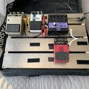 Kytarový pedalboard v černém přepravním kufru s několika efekty. Jsou zde pedály s nápisy CHORUS C1, Delay a ULTRA METAL UM300 od značky behringer. V…