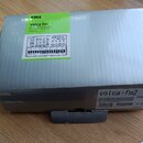 Kartonová krabice s nástrojem KORG volca fm. Na horní straně je zelený štítek s nápisy KORG, volca fm, DIGITAL FM SYNTHESIZER a volca fm2. Na boční s…