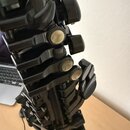 Detailní záběr na mechanismus černého dechového nástroje, pravděpodobně klarnetu. Jsou vidět kovové klapy s perleťovými vložkami a černé plastové neb…