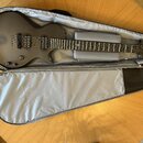 Matně černá elektrická kytara v otevřeném šedém softcasu. Na hmatníku je vidět bílý nápis "ESP". Kytara má dva humbuckery, ovládací knoflíky a na hor…