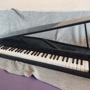 Černé digitální piano v provedení křídla s otevřeným víkem. Nástroj má standardní klávesnici s bílými a černými klávesami. Na povrchu nejsou viditeln…