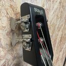 Černá hlava kytary s nápisem Stagg. Na zadní straně jsou dva kovové ladičky s viditelným opotřebením povrchu. Přes hmatník vedou čtyři struny, z nich…
