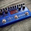 Modrý efektový pedál s nápisy OCEAN MACHINE a MOOCR Looper. Zařízení má v horní části řadu černých otočných knoflíků, uprostřed malý displej a ve spo…