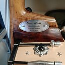 Detail zadní strany hlavy a krku akustické kytary z dřeva. Na krku je kovový oválný štítek s nápisy Ovation, Celebrity elite, Limited edition a NO. 0…