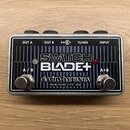 Kytarový pedál v kovovém stříbrném šasi s černým čelem. Na povrchu jsou nápisy SWITCH BLADE+, electro-harmonix a NEW YORK CITY, USA. Jsou zde dva kov…