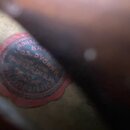 Detail vnitřku nástroje s červenou kulatou nálepkou. Na nálepce je černý text, ze kterého jsou čitelné nápisy JOS. DVORAK a PRAHA II, SPILBERK UL 24.…