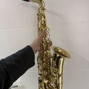 Zlatý saxofon s černým mouthpiecem. Nástroj je v dobrém vizuálním stavu, povrch je lesklý bez viditelných škrábanec nebo naleptání. Na fotce nejsou ž…