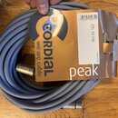 Šedý svitek kabelu s kovovými konektory. Na přiloženém kartónovém obalu je žluté logo CORDIAL s nápisem we are cable, bílý nápis peak a označení mode…