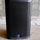 Černý reproduktor v hranatém provedení s kovovou mřížkou. Ve spodní části je umístěno kulaté modré logo s nápisem Q Turbosound. Povrch je v dobrém st…