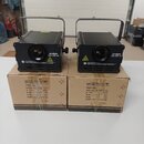 Dvě černé laserové jevové světla s rukojetí, umístěná na svých kartonových krabicích. Na přední straně každého přístroje je nápis „volights Laser RGB…