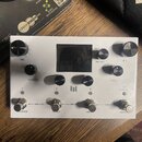 Bílý efekt pedál s černým displejem uprostřed. Na přístroji jsou ovládací knoflíky s popisky TIME, FEEDBACK, PRESET/PAGES (SAVE HOLD), MIX a MOD. V d…