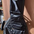 Černý polstrovatý pouzdro (gig bag) na kytaru z syntetického materiálu. Na přední kapse je umístěna malá štítková značka s nápisem ROCKBAG. Pouzdro m…