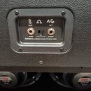Detail zadní strany kytarového reproduktoru s černým povrchem. Jsou zde dva vstupy typu jack, přepínač MONO/STEREO a nápisy 8 Ω 16, RIGHT, LEFT a var…