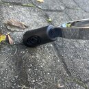 Detailní záběr na konec kovového předmětu s černým plastovým nebo gumovým návlekem. Povrch černého návleku vykazuje známky opotřebení a v místě spoje…