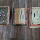Tři staré notové seпиты položené na dřevěné podlaze. První kniha zleva má nápis „Česká opera pro mladé pianisty“, „B. SMETANA“ a „PRODANÁ NEVĚSTA“. P…